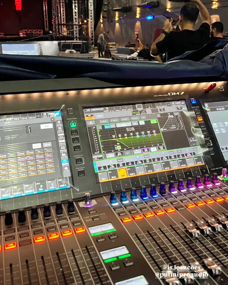 Mesa de som digital com telas e faders iluminados durante uma gravação