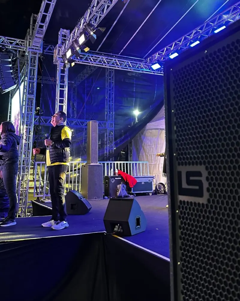 Palco com treliça iluminada em azul e subwoofer LS Audio na lateral