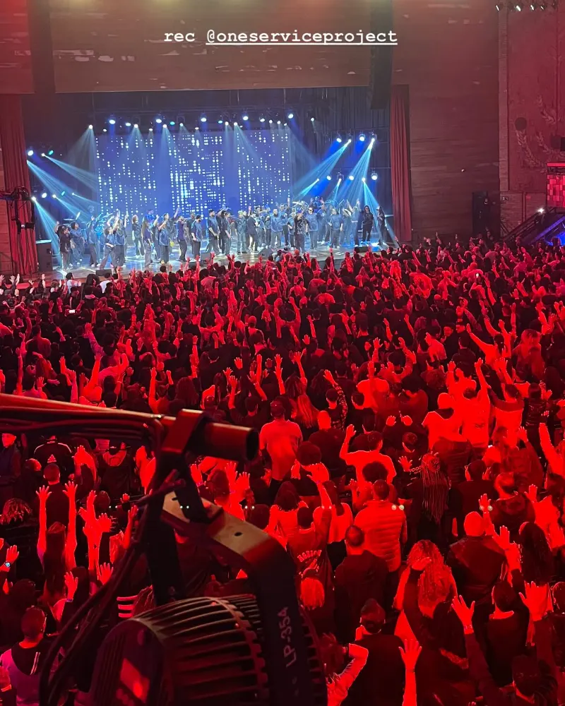 Público em show com luz vermelha e telões azuis no palco