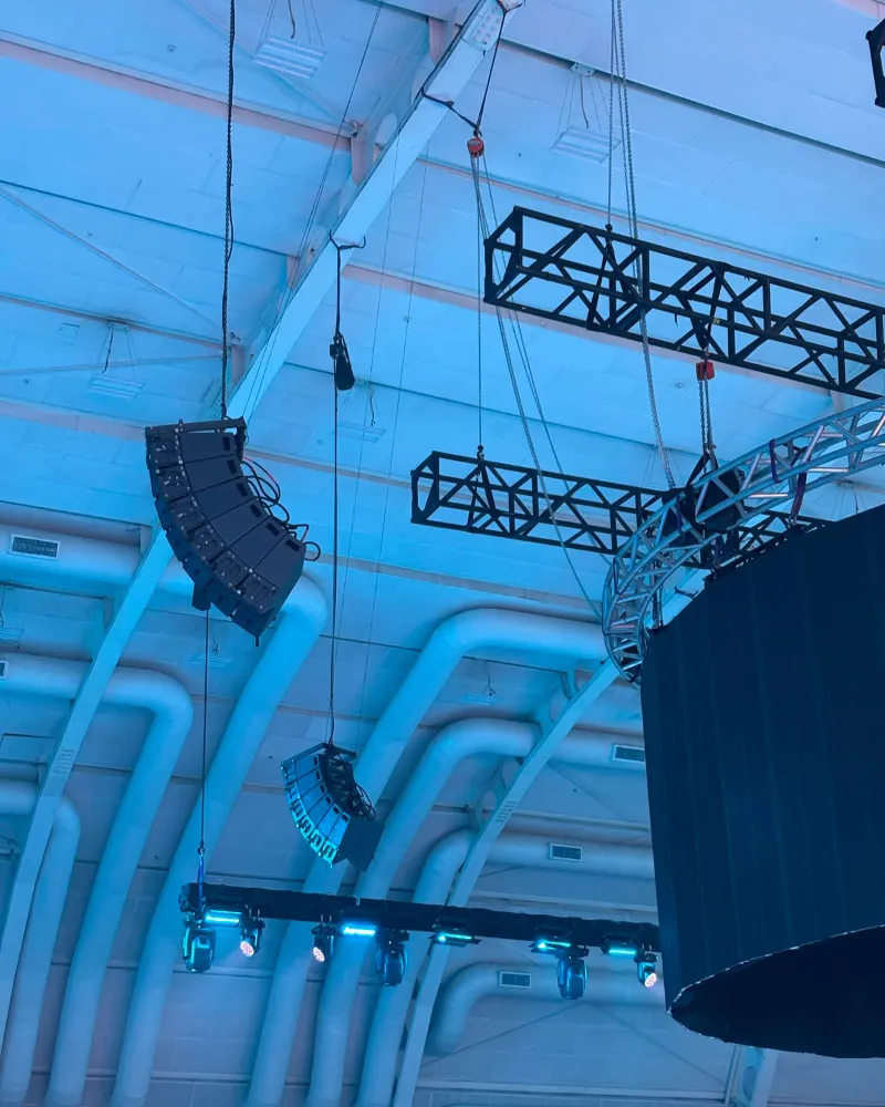 Dois line arrays pendurados no teto do WTC São Paulo, com uma vara de moving heads abaixo